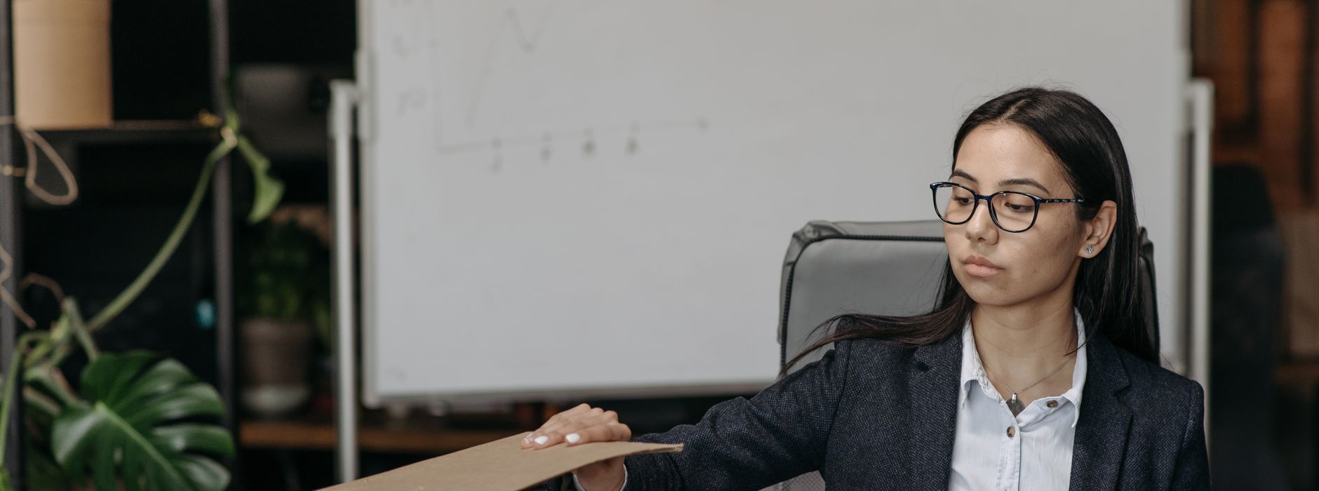 An administrator with glasses reviews a folder at her office desk
